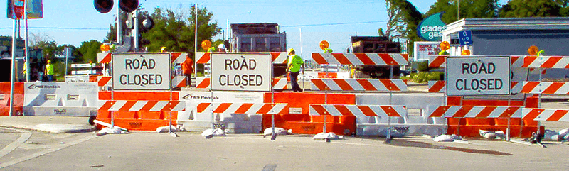 Road with barricades and road closed signs blocking other side.