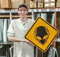 man holding yellow sign with black alien head